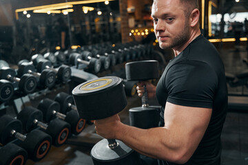 Tranquil bodybuilder with hand weights posing for camera