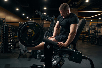 Sportsman performing leg exercise using gym equipment