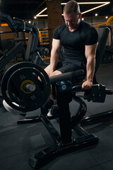Fototapeta na wymiar Bodybuilder doing strength-training exercise using fitness equipment
