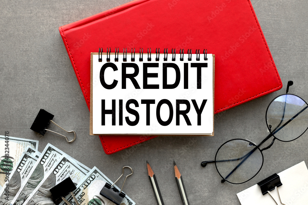 Poster credit history text in open notepad on red notepad on gray background