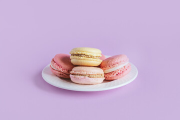 Tasty french macaroons on a violet pastel background.