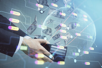 Double exposure of world map drawing hologram and us dollars bills and man hands.