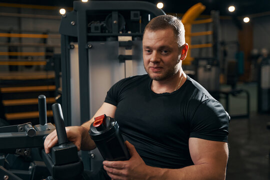 Athlete with healthy beverage seated on exercise machine