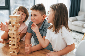 Building a tower. Playing game. Kids having fun in the domestic room at daytime together