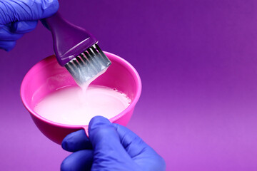 Hairdresser mixes hair dye in a plastic bowl