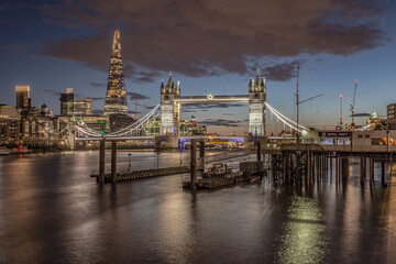 The iconic Tower Bridge in London, view to the illuminated Tower Bridge and skyline of London, UK, just after sunset.