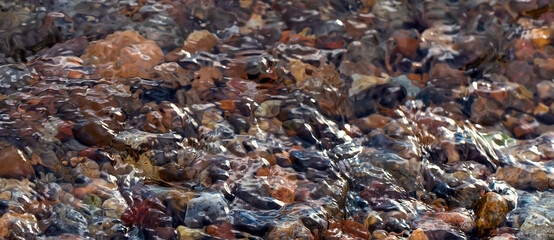 Abstract background with colorful round sea pebble stones texture on the shore. Banner.