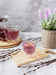 Cup of purple drink with flowers, on grey background