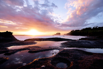 Beautiful balinese landscape. Ancient hinduism temple Tanah lot on the rock against sunset sky. Bali Island, Indonesia.