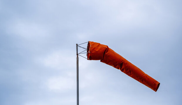 Windsock blow on cloudy sky. Red cone for wind speed and direction at the airport