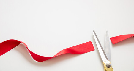 Grand opening, ribbon cut, overhead of gold scissors and red satin satin isolated on white