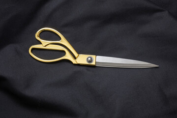 Overhead of gold scissors on black cloth. Tailor, barber tool, fashion concept
