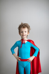 Superhero Kid. Dreamy boy in red cape against a gray wall