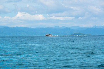 Naklejka premium Motor Yacht Sails Fast Near a Tropical Island