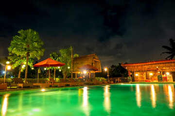 Fototapeta na wymiar Night Swimming Pool with Bar in a Tropical Hotel