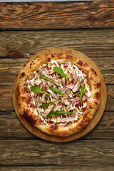 neapolitan Pizza with Mozzarella cheese, bacon, ham, tomato sauce, chicken, Spices and Fresh arugula. Italian pizza on wooden table background