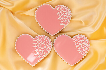 background banner greeting card for valentine's day with gingerbread pink heart icing cookies with on silk fabric background