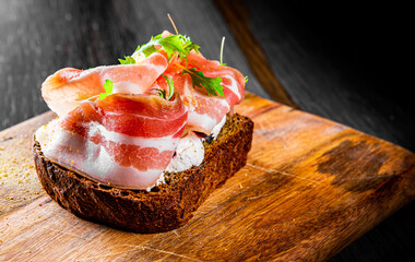 Bruschetta with prosciutto bacon and cream cheese on wooden plate