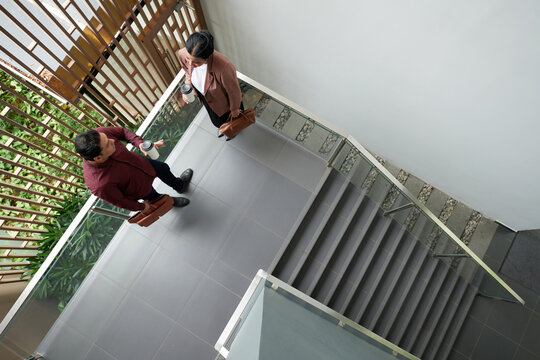 Business people standing on stairs, drinking morning coffee and discussing work