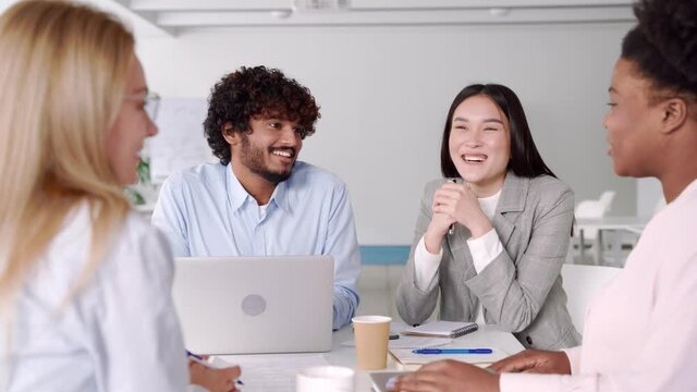 Multi-ethnic diverse students working on common project sitting at desk in class