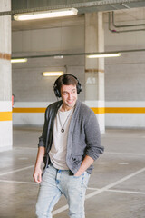 portrait of fashionable cool man on an industrial environment listening to music with earphones. vertical shot. High quality photo
