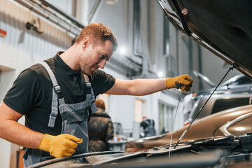 Ready to solve the problem. Man in uniform is working in the auto service