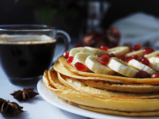 pancakes with bananas and pomegranate seeds, and coffee