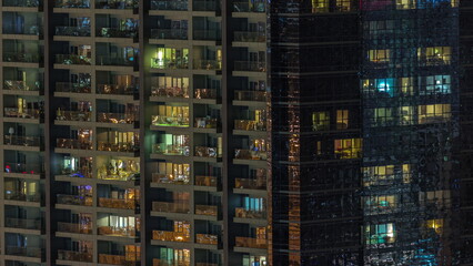 Fototapeta na wymiar Windows of apartment building at night timelapse, the light from illuminated rooms of houses