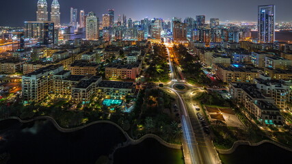 Obraz premium Skyscrapers in Barsha Heights district and low rise buildings in Greens district aerial night timelapse.