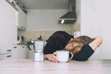 Tired sleepy person female having some problems. Exhausted woman with coffee at home. Сoncept of woman or mother in depression, burnt out, tired from work or study, unsatisfactory with life.