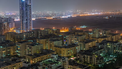 Skyscrapers in Barsha Heights district and low rise buildings in Greens district aerial night timelapse.