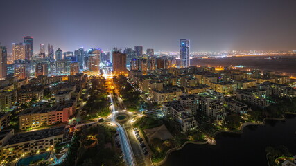 Obraz premium Skyscrapers in Barsha Heights district and low rise buildings in Greens district aerial all night timelapse.