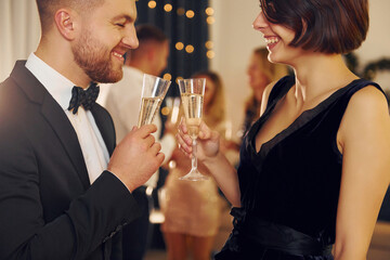 Cheerful couple. Group of people have a new year party indoors together