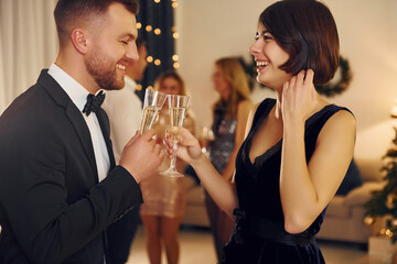 Cheerful couple. Group of people have a new year party indoors together