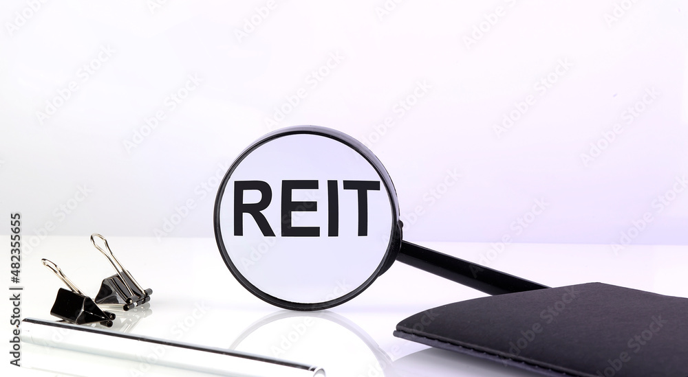 Poster reit text concept. magnifier glass with text with notebook and pen
