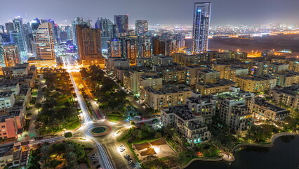 Obraz premium Skyscrapers in Barsha Heights district and low rise buildings in Greens district aerial all night timelapse.