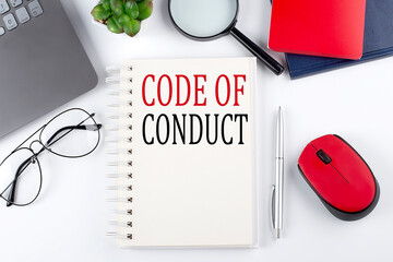 CODE OF CONDUCT text on a notepad with laptop on the white background