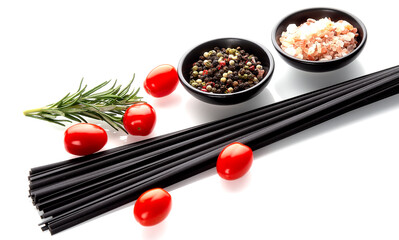 Raw black spaghetti pasta with tomatoes and spices on white background. Dry black macaroni.