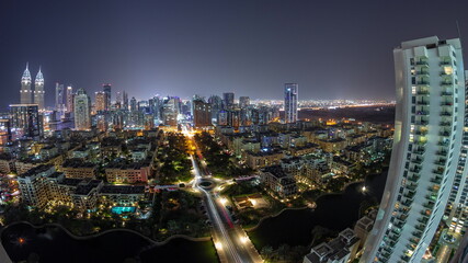 Fototapeta na wymiar Panorama with skyscrapers in Barsha Heights district and low rise buildings in Greens district aerial night timelapse.