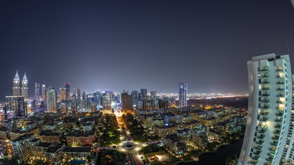 Fototapeta na wymiar Panorama with skyscrapers in Barsha Heights district and low rise buildings in Greens district aerial all night timelapse.