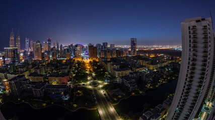 Fototapeta na wymiar Skyscrapers in Barsha Heights district and low rise buildings in Greens district aerial night to day timelapse.