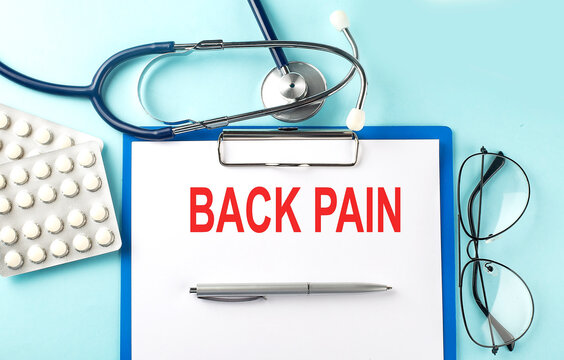 Paper with text BACK PAIN on a blue background with stethoscope and pills