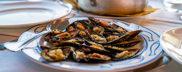 Mussels with herbs in a bowl with lemon on a white wooden table. Seafood. Food at the shore of the...