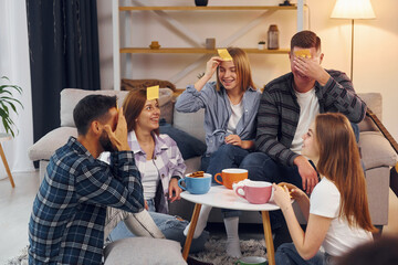 Playing who am I game. Group of friends have party indoors together