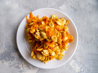 Top view of a white plate with raw pumpkin seeds.
