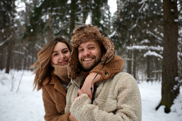Fototapeta premium People, season, love and leisure concept - happy couple hugging and laughing outdoors in winter. Couple embracing and having fun in snowy winter park