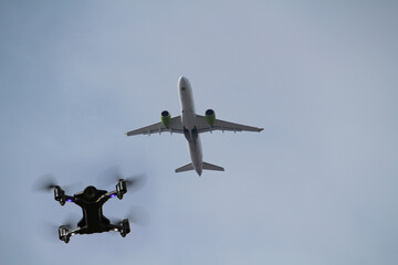 Fototapeta na wymiar Air drone flying below airliner against blue sky