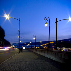 Fototapeta na wymiar Night view of a sidewalk with blurry human silhouette and light trails.
