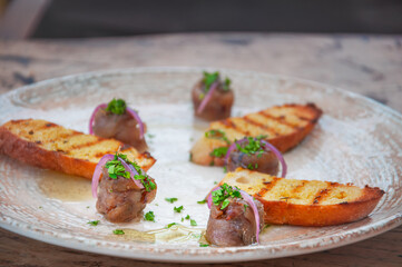 Grilled bread slices with olive oil, herbs and roll anchovies. Spanish bar food anchovy tapas