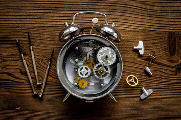 Watch mechanism and watchmaker tools near open alarm clock